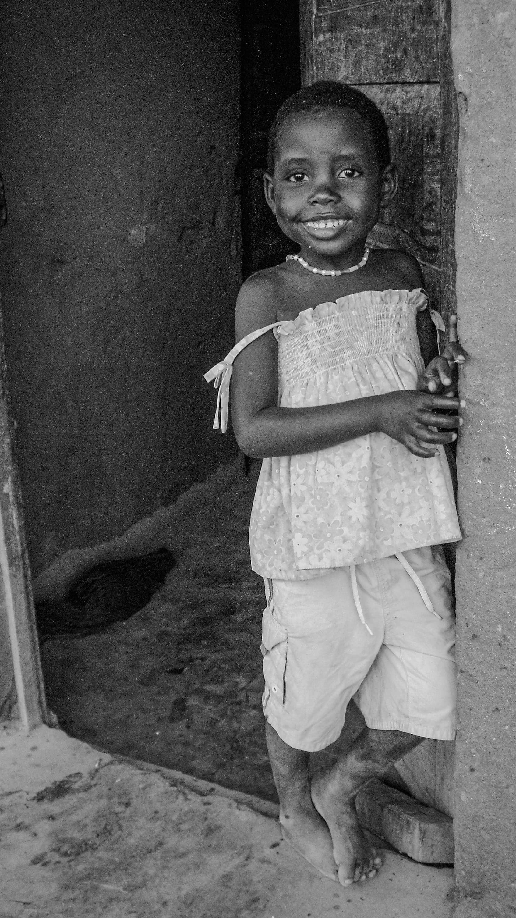 A local schoolgirl smiling in a doorway at a children's center in Pemba, Mozambique
