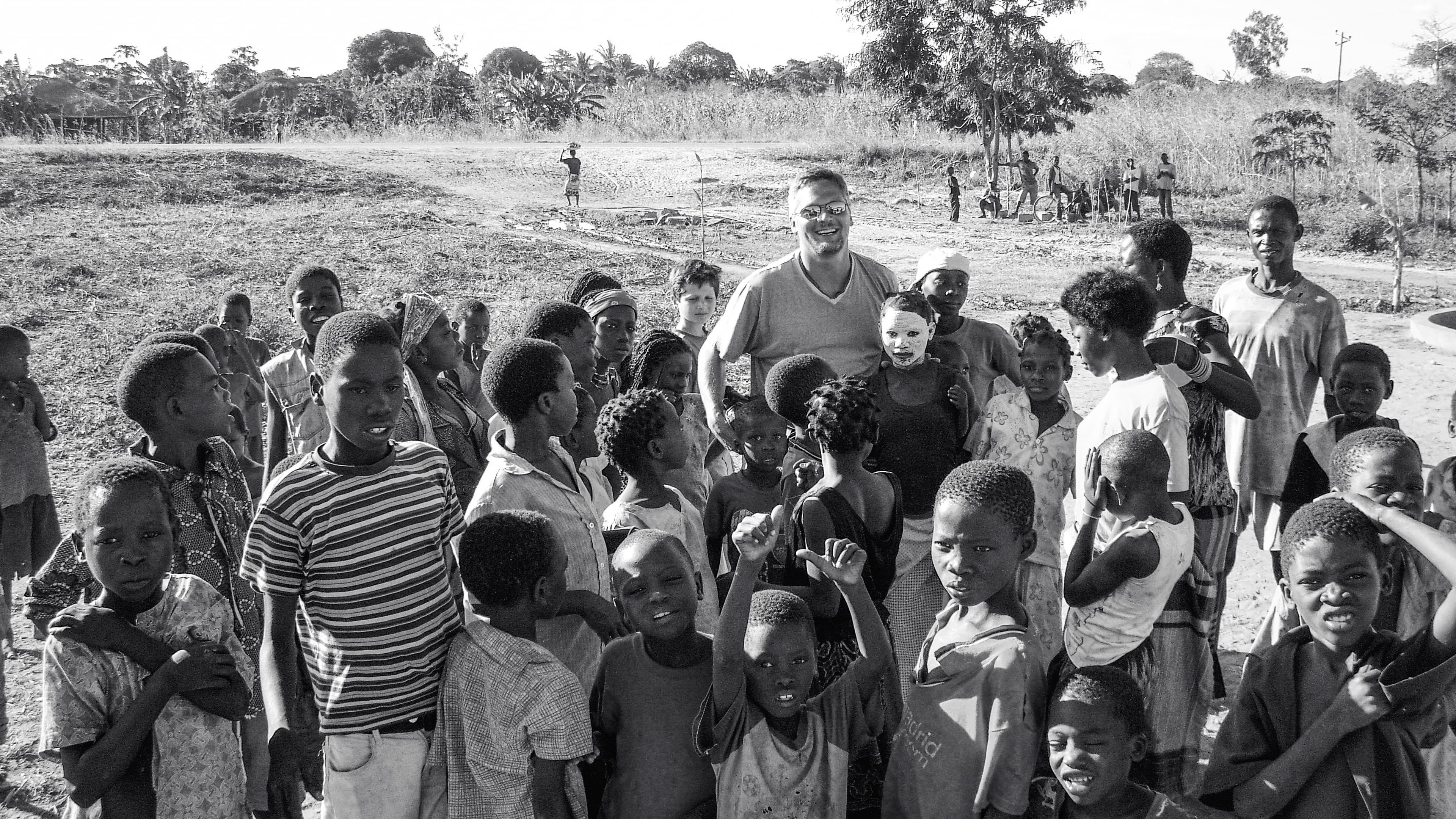 Chad standing with a group of adults and children in an open clearing