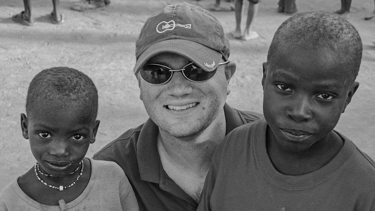 Chad smiling between two boys, wearing a cap and sunglasses