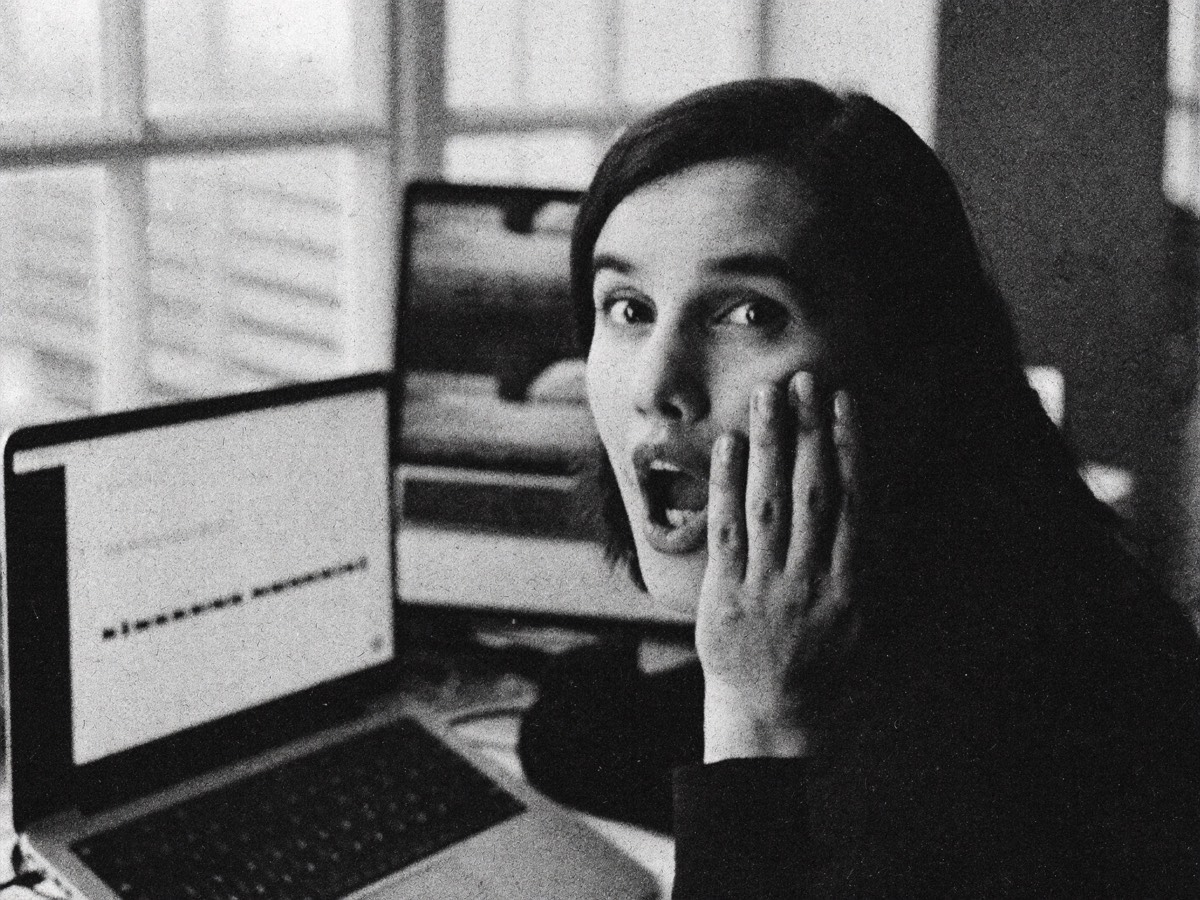 A founder at their desk, hand to cheek, stunned by what their laptop screen is showing them