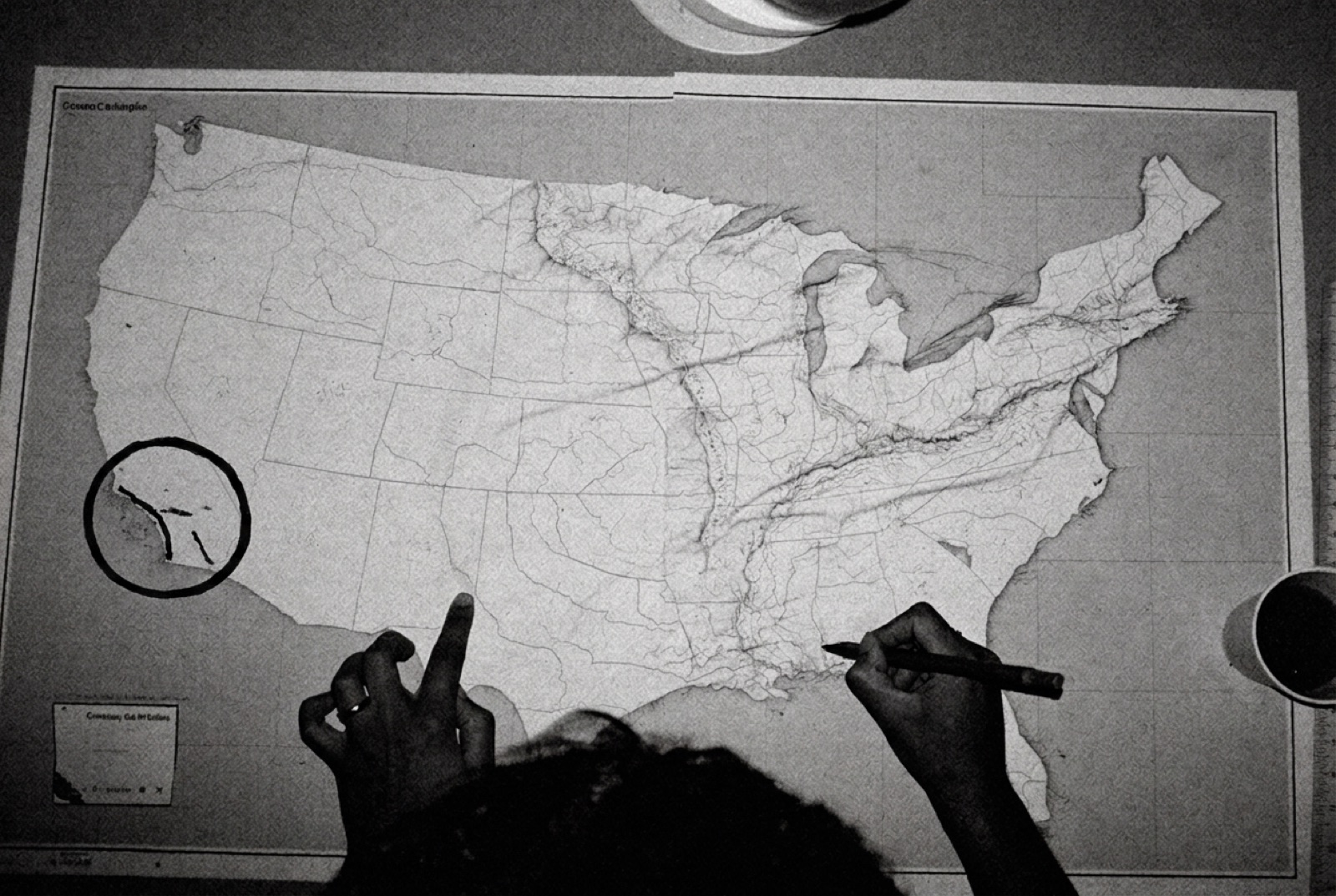 Hands drawing a grease-pencil circle around Southern California on a printed map of the United States